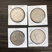 Reverse side of 4 Canadian silver dollars showing the Voyageur and canoe design on three coins and a hummingbird design on one coin.