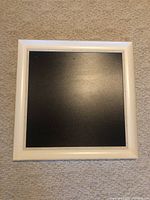 Front view of the chalkboard showing a white wood frame surrounding black chalkboard surface.