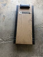 Top view of Motomaster mechanic creeper showing tan pad and padded headrest with black metal rails on sides.