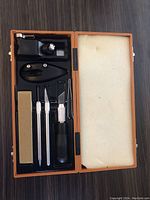 Open view of the precision cutting kit showing blade holder, blades, blade handle, and sharpening stone.