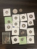 Top down view of various Canadian silver coins in individual holders and plastic bags on a wooden surface