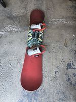 Top view showing red top base and attached Burton bindings with white straps and red highbacks.