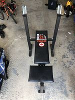 Photo showing full weight bench from above, displaying the padded backrest and seat area with metal uprights for weights or barbell support.