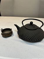 Front view of cast iron hobnail teapot with lid in place and brass bowl