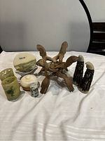 Overview of all items in lot on table with white cloth including wooden hands, marble containers, salt and pepper shakers, candle holders.