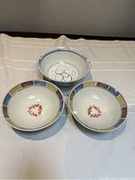Top view of the three bowls showing the interior designs: one plain with blue flower, and two with multicolor borders and central motifs