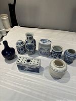 Full view of the lot showing eight blue and white porcelain items including vases and jars arranged on a white surface.