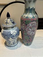 Two Asian porcelain vases displayed side by side on a table showing size and color contrast