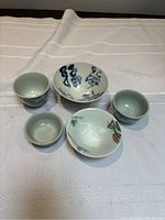 Overall view of all five porcelain cups and bowls on cloth background