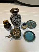 Six cloisonné items arranged front-facing: large black and white vase, two smaller vases, teapot, dish, ashtray