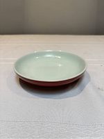 Front-angle view showing interior celadon glaze and red exterior