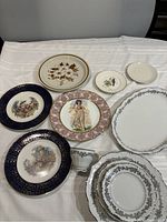 Top view of collection showing all plates and teacup on white cloth, showcasing different designs and sizes.