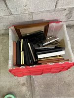 Photo showing a bin with multiple photo frames of different sizes and colors stacked inside.