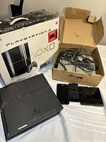Overview showing PlayStation 3 box, PS4 console, box of cables/controllers, and four smartphones