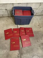 Container of multiple red hardcover books titled 'The World Its Peoples' shown on floor and inside large blue plastic bin.