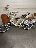 Side view of cream folding bicycle showing front basket, two seats and frame graphics