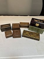 Seven wooden decorative boxes arranged on a table showing variety of designs and sizes.