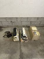 Photo showing two vintage sewing machines side by side with cords and accessories.