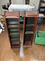 Open view of two narrow vintage bookcases, displaying interior shelf count and condition.