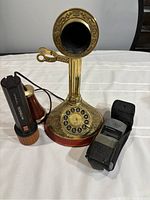 Full view of vintage candlestick phone with rotary dial, alongside a Duracell Durabeam flashlight and a black pager device.