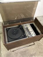 Full view of vintage wooden console with vinyl record player and radio controls, dust cover open.
