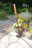Full view of the branding iron standing outside showing the wooden handle and metal branding end shaped as letters 'AU'