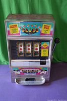 Front view of Casino Grand slot machine showing colorful light-up panel, three reels with fruit and bell symbols, coin slot, and handle.