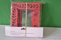 Four orange plastic 6 inch clamping squares in original packaging secured by a rubber band.