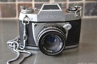 Front view of the Exakta 500 camera with attached Meyer-Optik lens and metal chain on gray surface.
