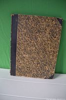 Hardcover book with marbled cover and black spine shown closed.
