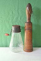 Glass and wooden butter churns displayed side by side on a green cloth background
