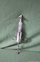 Photo of a used Becton Dickinson Cornwall scientific syringe, metal and glass construction, 9 inches long, graduated in 0.2 cc