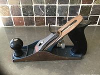 Full side angle view showing the metal body with wooden handles and the black front knob.