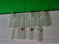 Clear glass test tubes, approximately 30 in total, laid out showing varying lengths between 3 and 5 inches. Some tubes have cork stoppers.