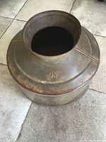 Side view of used large metal bowl with a wide central hole, marked with '25'. Shows the bowl's round shape, seam, and aged surface.