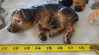 Large sleeping dog figurine with measuring tape showing length at approximately 17.5 cm