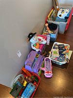 View of assorted children's toys including plush toys, plastic vehicles, bins with assorted small toys, and children's books