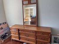 Full front view of vintage wooden dresser with nine drawers and attached mirror