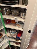 Shelves with stainless steel pots with lids, assorted mixing bowls, ramekins, other kitchen cookware and accessories.