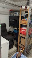 View of storage locker showing resin shelving unit with storage bins, recliner chair and ottoman