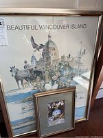 Framed 'Beautiful Vancouver Island' poster alongside a smaller framed still life painting under glass with metallic frames.