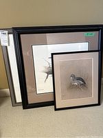 Three framed bird-themed art prints of varying sizes leaning against wall