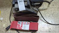 Craftsman belt sander with power cord and two sanding belts lying in front.
