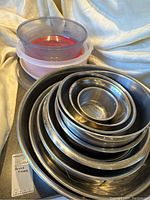 Nested metal mixing bowls with two plastic containers stacked on top