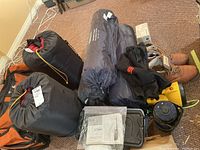 Overview of boots, sleeping bags, sleeping pads, yellow lantern and duffel bag