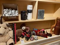 Image showing plush animal figures, metal toy motorcycles, a toy train, and various candles including tealights and pillar candles.