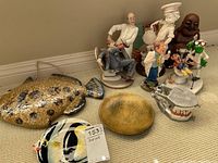 Overview of dentistry figurines, fish plaques and plates, and laughing Buddha figurine on carpeted floor.