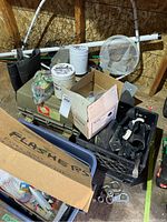 Photo of fishing gear including green rubber boots, various nets, boxes, and other tackle items