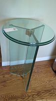 Full view of the glass side table showing the clear circular top and three glass legs.