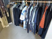 Hanging rack with multiple men's shirts and jackets in assorted colors and sizes large